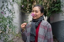 Junge Frauen in lässiger Kleidung berühren grüne Pflanzen, riechen Blumen und lächeln über geschaukelte Gasse — Stockfoto