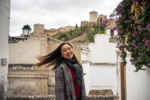 Asiatische Reisende in warmer Kleidung lächeln zwischen alten Gebäuden in der Nähe der großen Burg — Stockfoto