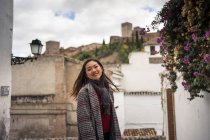 Asiatische Reisende in warmer Kleidung lächeln zwischen alten Gebäuden in der Nähe der großen Burg — Stockfoto
