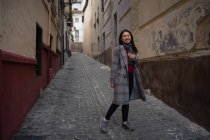 Fröhliche asiatische Ruhefrau wandert auf alter, geschockter schmaler Straße — Stockfoto