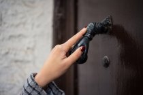 Hand of female traveler clattering in ancient door at city street — Stock Photo