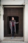 Eccitato asiatico viaggiatore femminile in casuale cappotto sorridendo mentre uscendo da piccola porta e vecchio edificio e guardando via — Foto stock