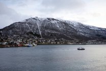 Von oben ruhige Bucht mit Stadt an der Küste sauberer mächtiger schneebedeckter Berg mit wolkenverhangenem Himmel im Hintergrund bei Tromsö in Norwegen — Stockfoto