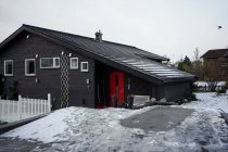 Große schwarze Scheune gegen schneebedeckten Hügel und Wohnhäuser im Grünen — Stockfoto