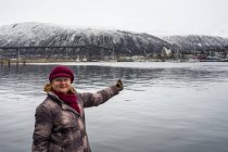 Seniorin in warmer Kleidung zeigt auf schöne Landschaft — Stockfoto