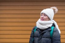 Junge asiatische Touristin in warmer Kleidung neben Holzhaus zum Spazieren — Stockfoto