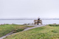 Женщина сидит на скамейке в дождливый день — стоковое фото