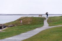 Мандрівник з парасолькою, що йде на підвищеному березі — стокове фото