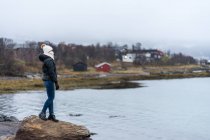 Feminino em pé no penhasco de pedra ao largo da costa — Fotografia de Stock