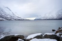 Vistas panorámicas desde piedras marinas sobre montañas nevadas - foto de stock
