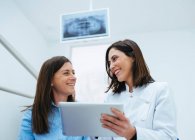 Dentista hablando con el cliente mostrando documento con información - foto de stock