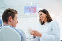 Lächelnder Zahnarzt und Assistent zeigt Struktur der Zähne bei Profis — Stockfoto