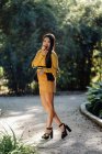 Graziosa bruna dai capelli lunghi donna asiatica con mela alla luce del sole sulla strada del giardino nel parco guardando la fotocamera — Foto stock
