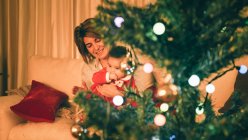 Mother playing with baby near Christmas tree — Stock Photo