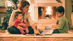 Mãe leitura livro com filho na véspera de Natal — Fotografia de Stock