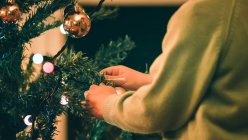 Immagine ritagliata del ragazzo che decora l'albero di Natale in serata — Foto stock