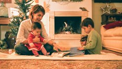 Mutter liest an Heiligabend mit Sohn Buch — Stockfoto