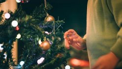 Immagine ritagliata del ragazzo che decora l'albero di Natale in serata — Foto stock