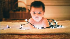 Baby playing with light garland on Christmas Day — Stock Photo