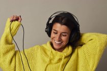 Playful young woman listening to music in studio — Stock Photo