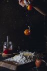 Рука людини, яка розбиває яйця на борошно, готуючи тісто на столі з яєчною шкаралупою та скляним горщиком — стокове фото