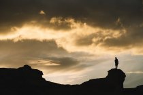 Dal basso di silhouette maschile in movimento sulla montagna con bel cielo nuvoloso sullo sfondo — Foto stock