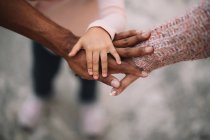 Close-up of diverse parents and child joining hands together outdoors at daytime — Stock Photo