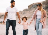 Happy diverse mother and father with curly child strolling on nature at daytime — Stock Photo