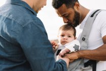 Multiracial fathers cuddling little baby outdoors — Stock Photo