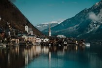 Splendide paysage de rivage pittoresque avec des bâtiments et des montagnes le long d'un lac cristallin calme reflétant ciel et nuages à Hallstatt — Photo de stock