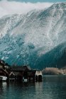 Paysage incroyable de maisons d'échasses en bois dans l'eau calme entourée de montagnes rocheuses enneigées à Hallstatt — Photo de stock