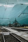 Empty railway and electric wires passing through mountains drowning in foggy haze in Hallstatt — Stock Photo