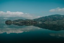 Спокойный пейзаж прозрачного озера, отражающего яркое бирюзовое облачное небо и холмистое побережье Зальцбурга — стоковое фото