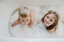 Смешные дети играют с пеной в ванной — стоковое фото