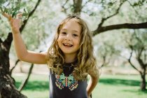 Sorridente ragazza arrampicata albero nella giornata di sole — Foto stock