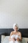 Adulto mulher relaxada desfrutando da vida enquanto descansa no sofá e tendo bebida quente após o chuveiro no próprio apartamento acolhedor — Fotografia de Stock