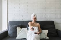 Glücklich entspannte Frau genießt freien Tag, während mit heißen Getränken nach der Dusche und Fernsehen in der Wohnung im Loft-Stil — Stockfoto