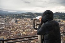 Rückansicht einer Frau, die auf einer Aussichtsplattform in der Nähe der Brunelleschi-Kuppel in Italien mit einem Fernglas antike Straßen von Florenz erkundet — Stockfoto