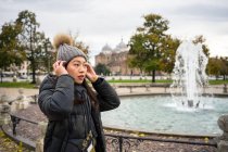 Side view of black haired female traveler in warm clothing and hat walking at beautiful old Prato della Valle park at Padova at Italy — Stock Photo