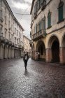 Femme voyageuse en vêtements chauds marchant sur la route de pierre bloc parmi les beaux bâtiments historiques à Padoue en Italie — Photo de stock