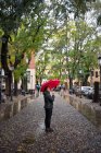 Jeune voyageuse asiatique en vêtements chauds en utilisant un parapluie rouge avec de vieux bâtiments sur fond flou à Padova en Italie — Photo de stock