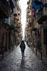 Rückansicht eines Touristen in warmer Kleidung, der die enge Steinstraße zwischen alten Gebäuden im spanischen Viertel von Neapel erkundet — Stockfoto