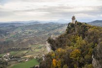Antike Burg auf einem Gipfel mit grünen Bäumen, die sich in den grauen Himmel in San Marino erheben, Italien — Stockfoto