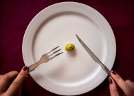 From above of crop female with knife and fork eating one green olive in restaurant of Malaga in Spain — Stock Photo