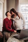 Casal esperando bebê beijando em casa — Fotografia de Stock