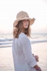 Femme en robe blanche pâle sur la plage ondulée — Photo de stock