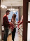 Young couple expecting baby arranging Christmas tree at home — Stock Photo