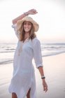Чарівна жінка в світло-білій сукні на хвилястому пляжі — стокове фото