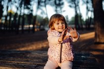 Adorable active kid in warm pink jacket in sunlight in park — Stock Photo