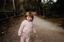 Adorable active kid in warm pink jacket in sunlight in park — Stock Photo